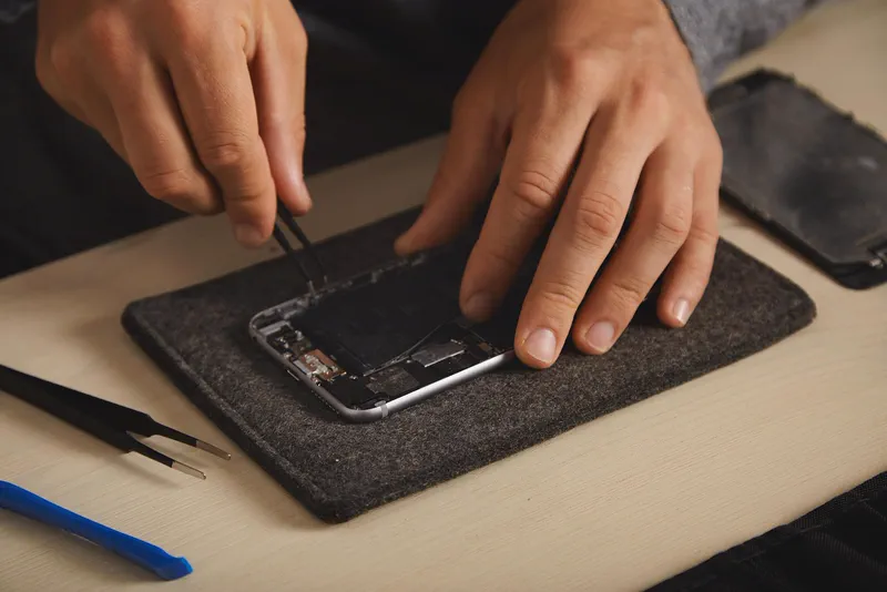 Mâini care repară un telefon, fotografie ilustrativă